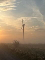 Obraz premium wind turbine in the field in the sunrise a foggy morning