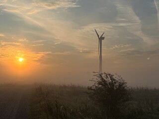 Obraz premium wind turbine in the field in the sunrise a foggy morning