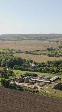 Straight aerial descent over rolling English farmland with fields and scattered trees