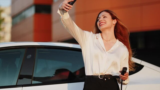 Young woman charges electric vehicle at urban charging station during sunny afternoon