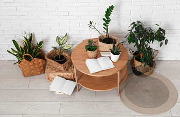 Table and wicker baskets with green plants near white brick wall in room