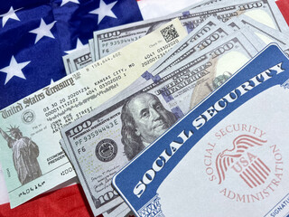 Social security card, us treasury check and currency bills on the American flag in the backdrop....