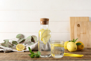 Glass and bottle of fresh lemonade with mint on wooden table