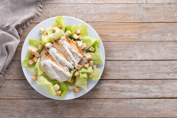 Crunchy Caesar salad with chicken on wooden table. Top view. Copy space