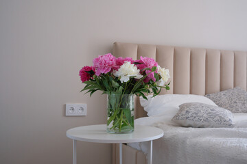 A Beautiful Peony Bouquet Arranged in an Elegant Glass Vase Sitting on a Side Table