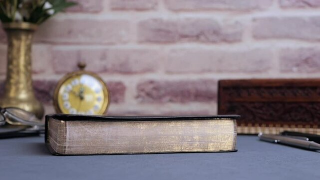 Bible falling for study on gray table with glasses and clock in the morning. Preparation for communion and worship concept. Slow motion