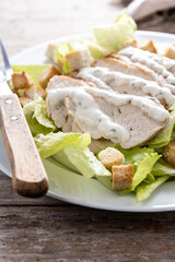 Crunchy Caesar salad with chicken on wooden table