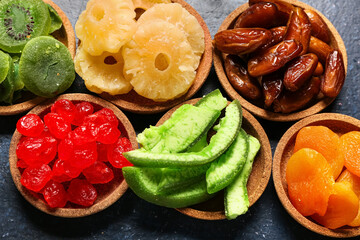 Bowls with different candied fruits on blue background, closeup