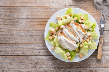 Crunchy Caesar salad with chicken on wooden table. Top view. Copy space