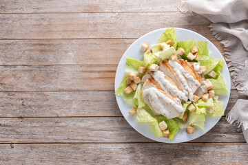 Crunchy Caesar salad with chicken on wooden table. Top view. Copy space