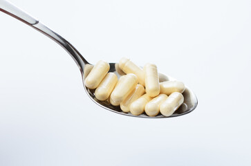 Spoon full of pills on white background