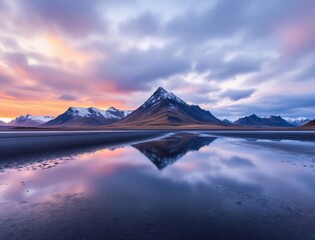 Majestic mountain range reflecting in calm water at sunset