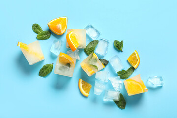 Ice cubes with fresh orange and mint leaves on blue background