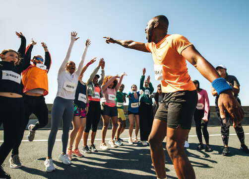 Dynamic running club with coach energizing the group - Powered by Adobe
