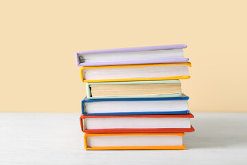 Stack of colorful books on white wooden table against beige background
