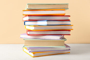 Stack of colorful books on white wooden table against beige background
