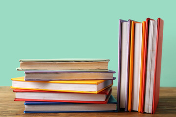 Many colorful books on wooden table against turquoise background