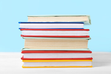 Stack of colorful books on white wooden table against blue background