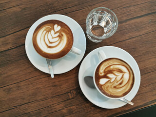 Two cups of hot latte coffee on a wooden table
