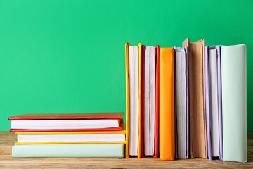 Many colorful books on wooden table against green background