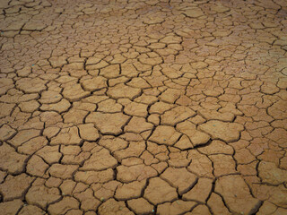 CLOSE UP: Dry, cracked earth reveals an intricate network of fissures across the parched surface. Pattern of the cracks emphasizes the severe effects of drought and arid conditions on the environment.