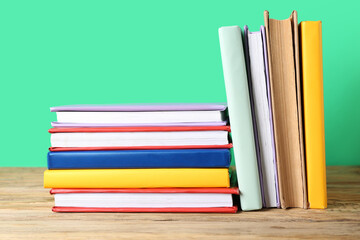 Many colorful books on wooden table against green background