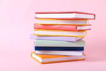 Stack of colorful books on pink background
