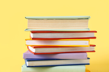 Stack of colorful books on yellow background