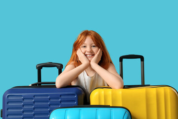 Cute girl with suitcases on blue background. Travel concept