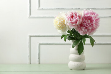 Vase with beautiful peony flowers on green wooden table