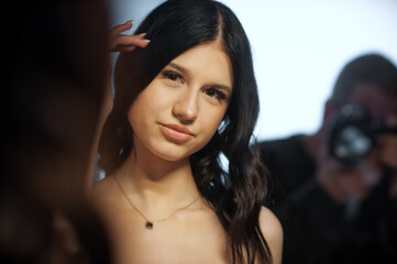 A young brunette woman poses elegantly for a modern fashion campaign. She is photographed by a professional in a well lit studio for use on social media