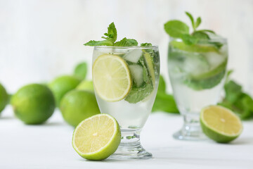 Glasses of fresh Mojito cocktail with limes and mint on white background