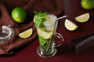 Glass of fresh Mojito cocktail with mint and limes on red background, closeup
