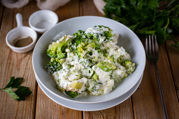 Healthy breakfast: broccoli with cream cheese in a white plate on a wooden table. Close-up