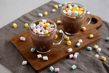 Warm Chocolate Cocoa in Mugs with Colorful Marshmallows, side view.