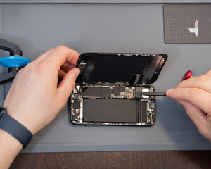 A technician disassembles a modern phone during a repair