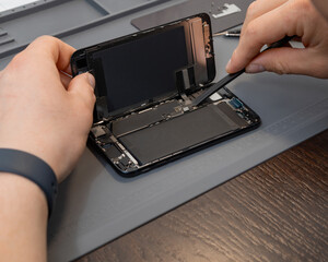 A technician disassembles a modern phone during a repair