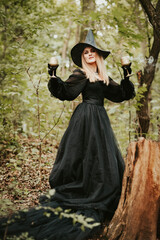 girl in a fluffy black dress and hat, halloween in the forest, magic with glasses
