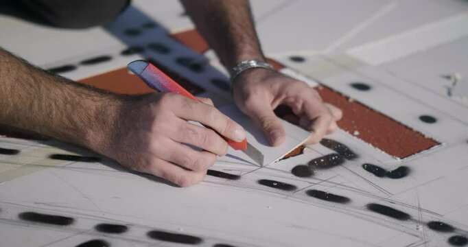 Hands measure and cut lines on building plan in precision architectural design process for stencil creation
