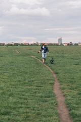 Young girl running with his dog in a large park in Berlin