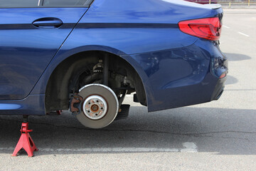 Rear Ceramic Brake Disc with Dismantled Calliper and Suspension Shock Absorber of a Car at Workshop