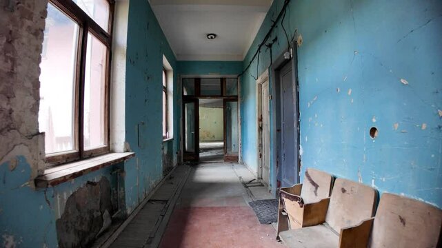Crumbling walls and peeling paint characterize the decaying hallway of the abandoned Sanatorium Gelati, a Soviet-era spa in Georgia, with broken chairs adding to the scene of desolation and neglect