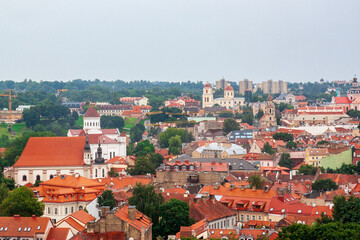 Obraz premium Cityscape of Vilnius, Lithuania from viewpoint in a summer cloudy day. View of the old town with orange tile roofs. Famous tourist destination. Travel photography.