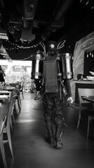 A futuristic explorer in cyberpunk gear wanders a dim restaurant, reminiscent of Steampunk Fest and RetroFuture Day