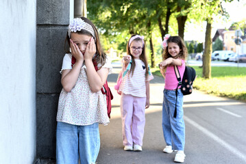 Peer violence of young children 7-8 years old. Three girls fight on the way to school