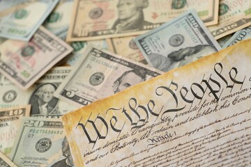 American US dollars money bills with coins and constitution close up on american flag