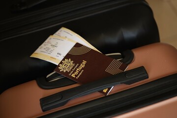 Portugese passport with tickets lies on touristic suitcase close up in airport waiting hall