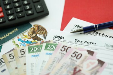 Mexican pesos money bills in big amount lies on table with pen, calculator, passport and tax forms