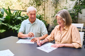 Senior couple enjoying brain games together in a rehabilitation facility garden