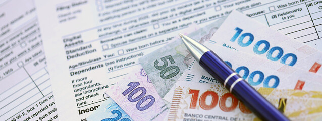 Argentine pesos money bills in big amount lies on table with pen and tax forms close up